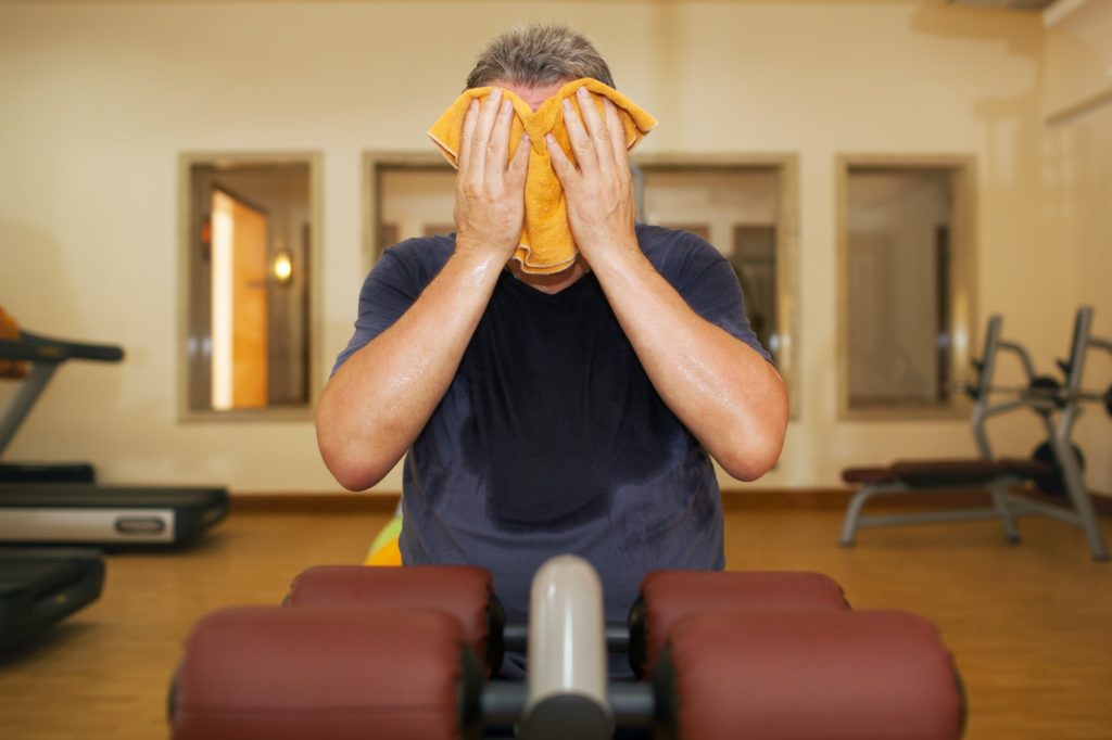 Man wiping face with a towel after training