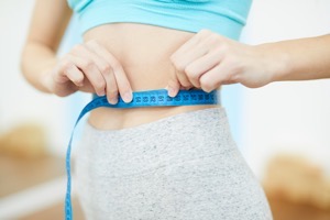 Unrecognizable woman measuring waist in gym YEX6URQ